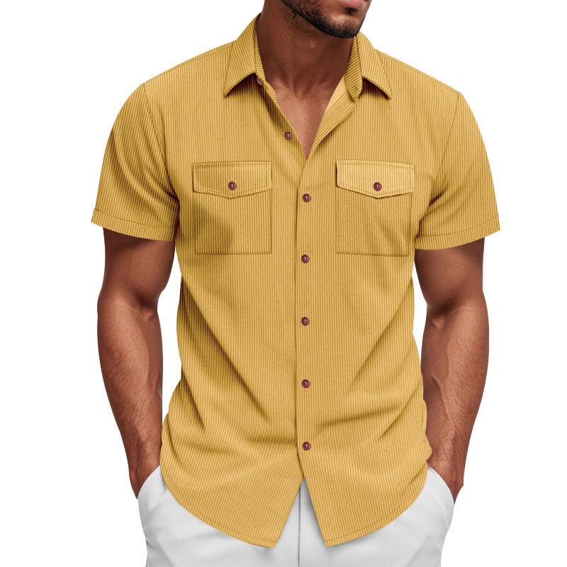 Man wearing a mustard yellow short-sleeve shirt with white pants on a white background
