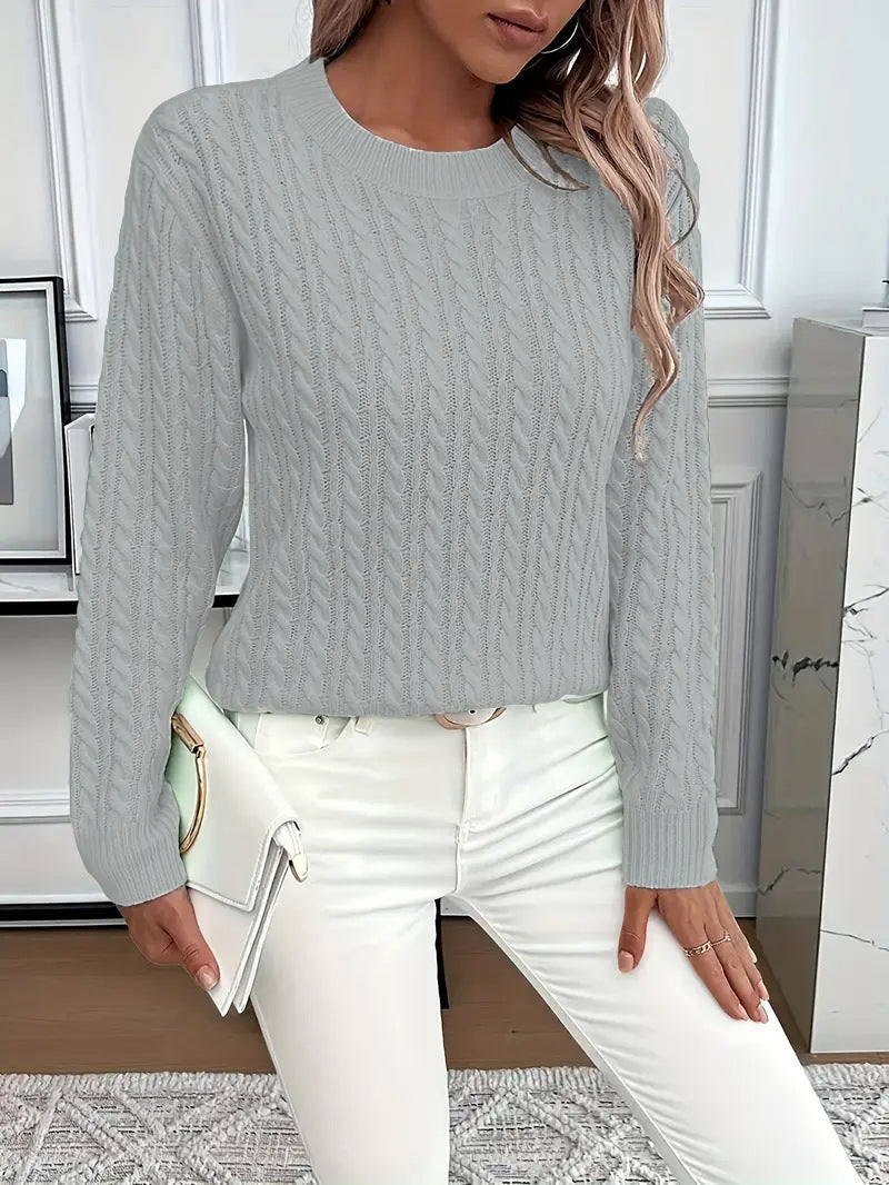 Person wearing a gray cable knit sweater and white pants in an indoor setting.