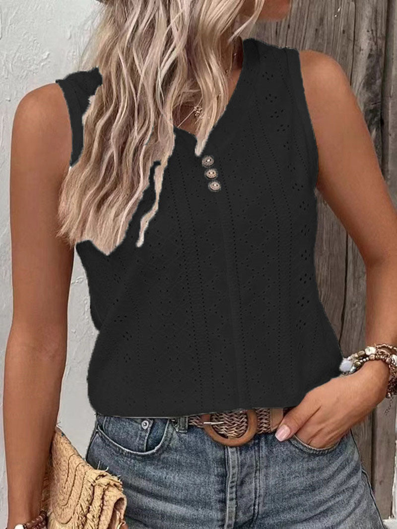 Person wearing a black sleeveless top with cut-out details and blue jeans, standing against a wooden wall.