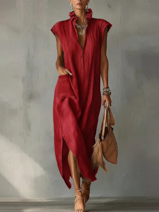 Woman wearing a red dress holding a brown bag against a gray wall.