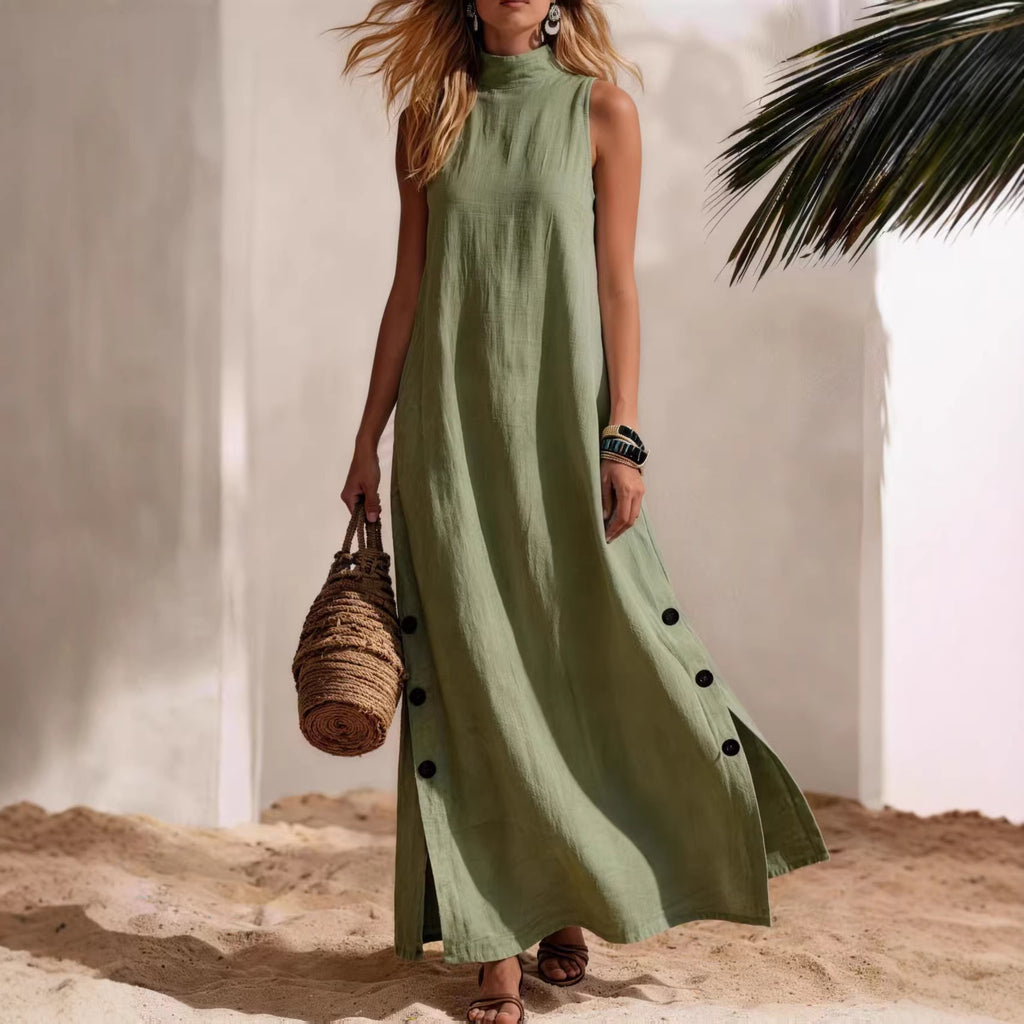 Woman in a long green dress standing on sand with a palm leaf in the background