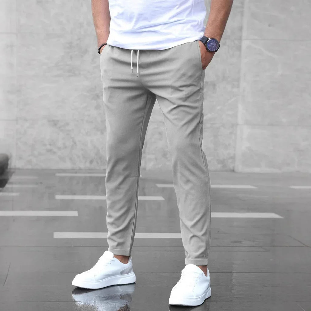 Person wearing light gray jogger pants with a plain background