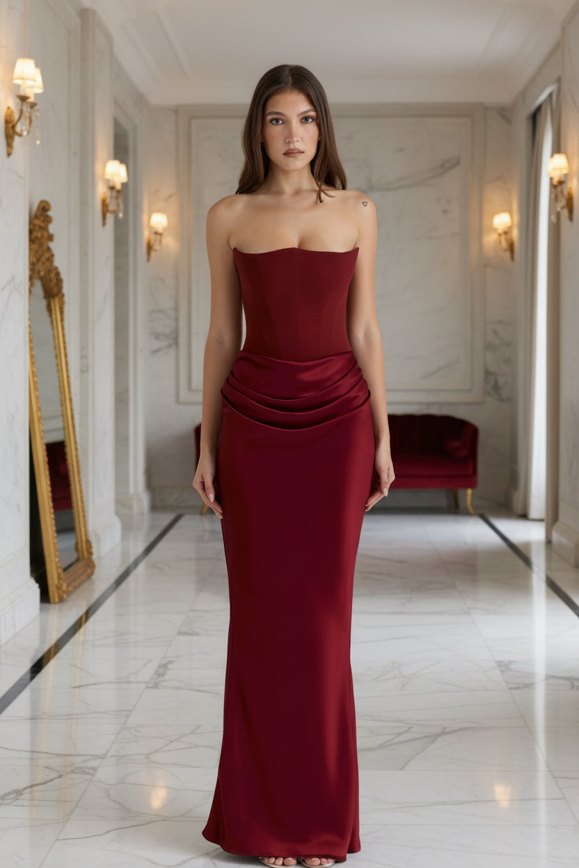 Woman wearing a strapless burgundy evening gown on a light gray background