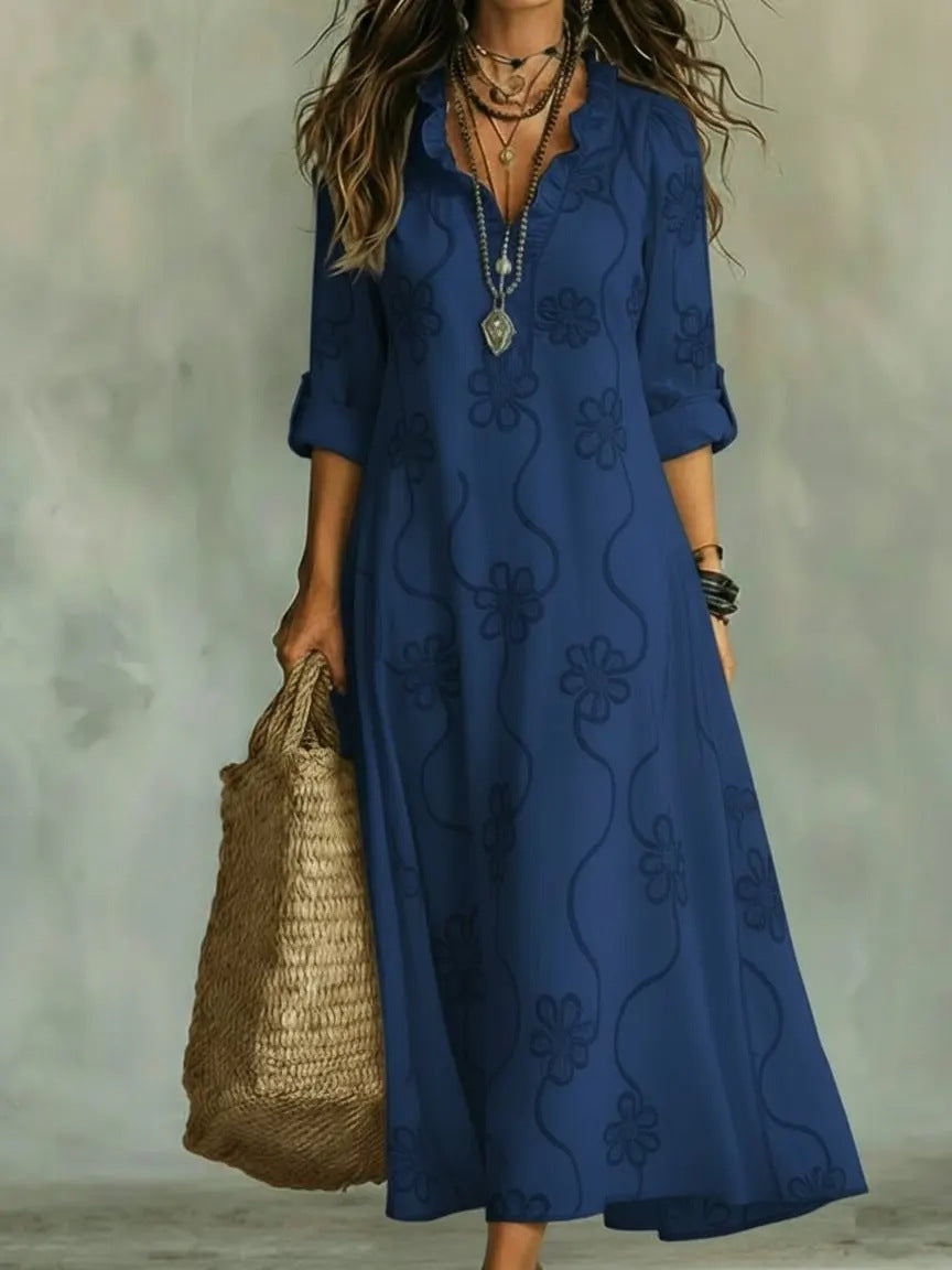 Woman wearing a blue embroidered dress holding a woven bag against a neutral background