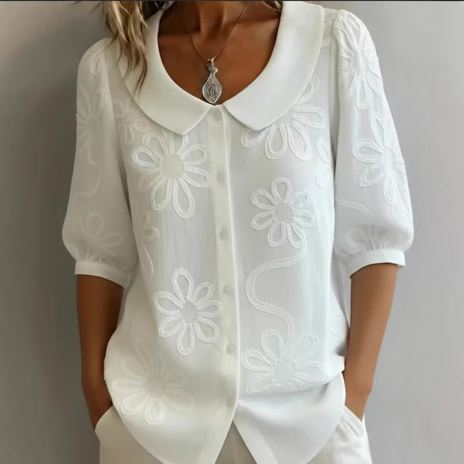 White blouse with floral embroidery on a plain background