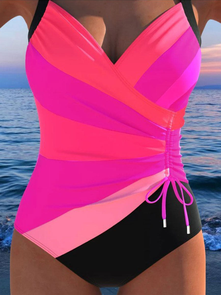 Pink and black swimsuit with ocean in the background
