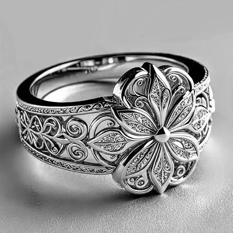 Silver ring with intricate floral design on a gray background