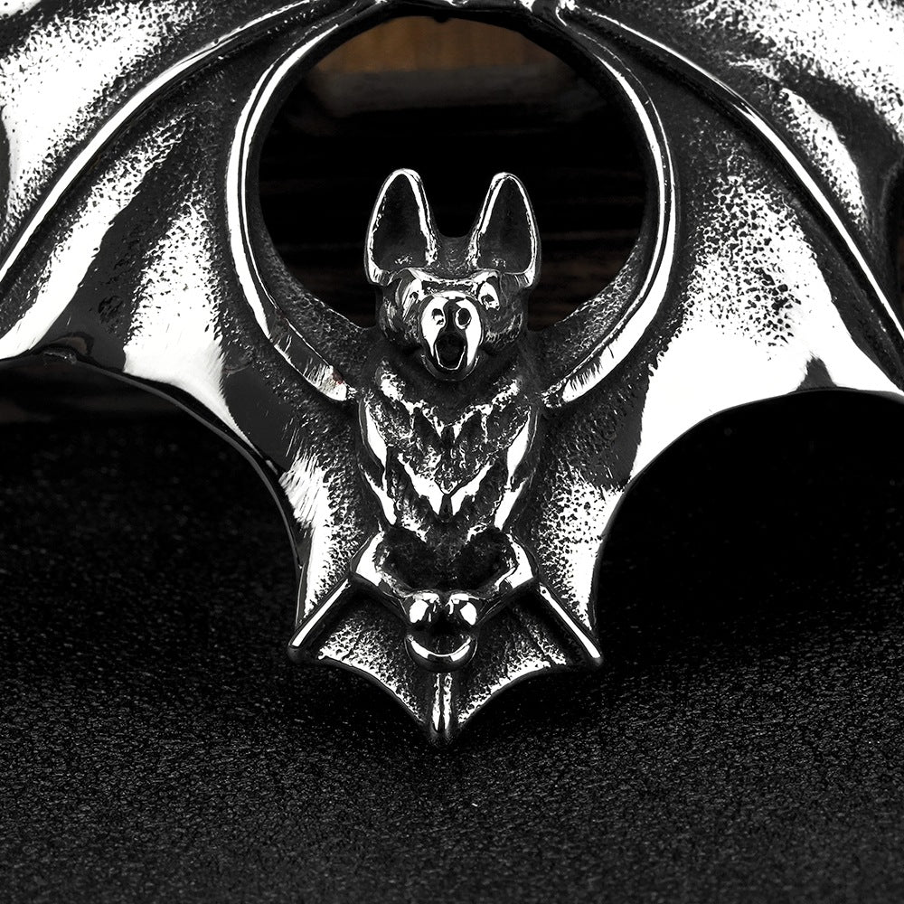 Metallic bat-shaped pendant with a detailed design on a dark background