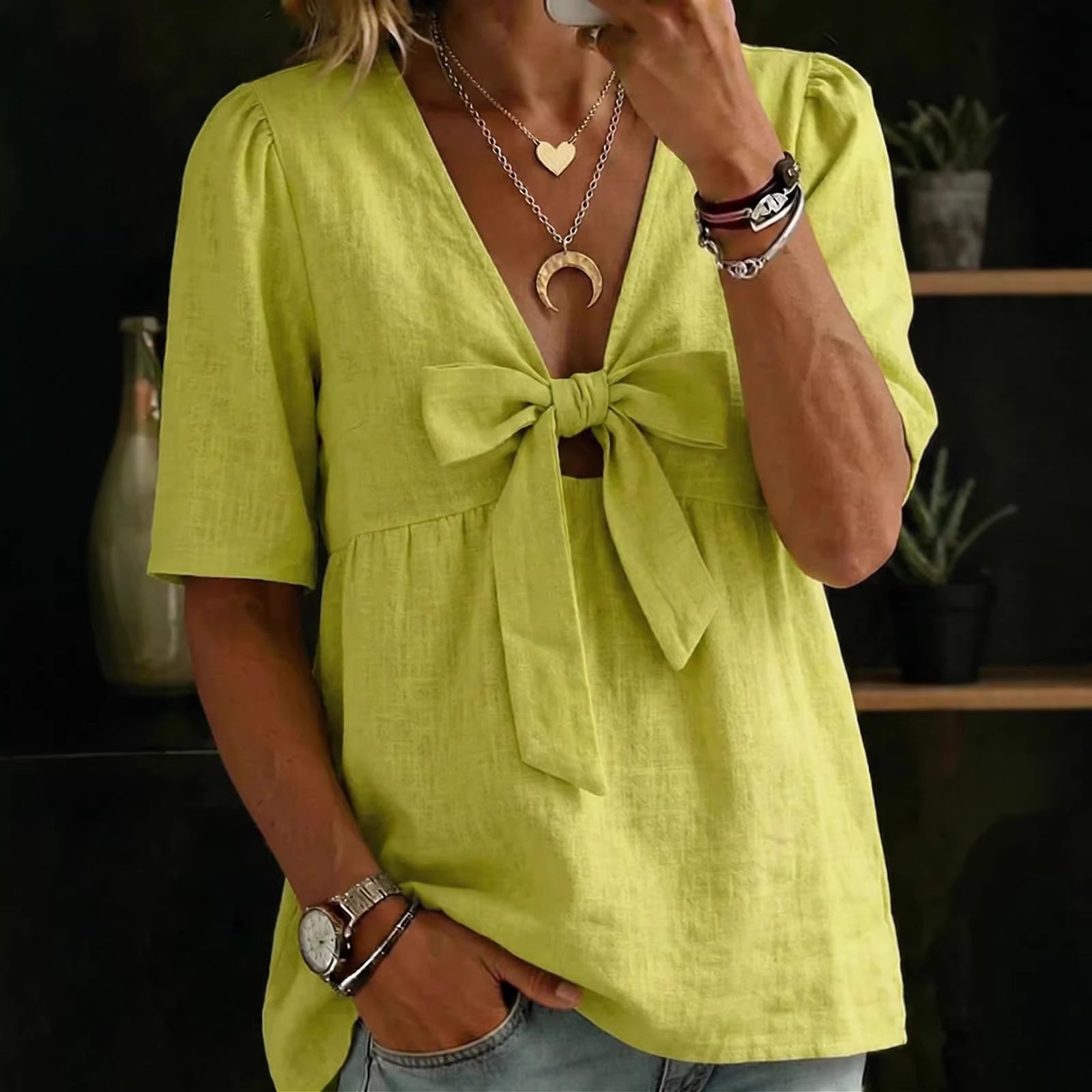 Person wearing a bright green blouse with a bow detail, standing indoors.