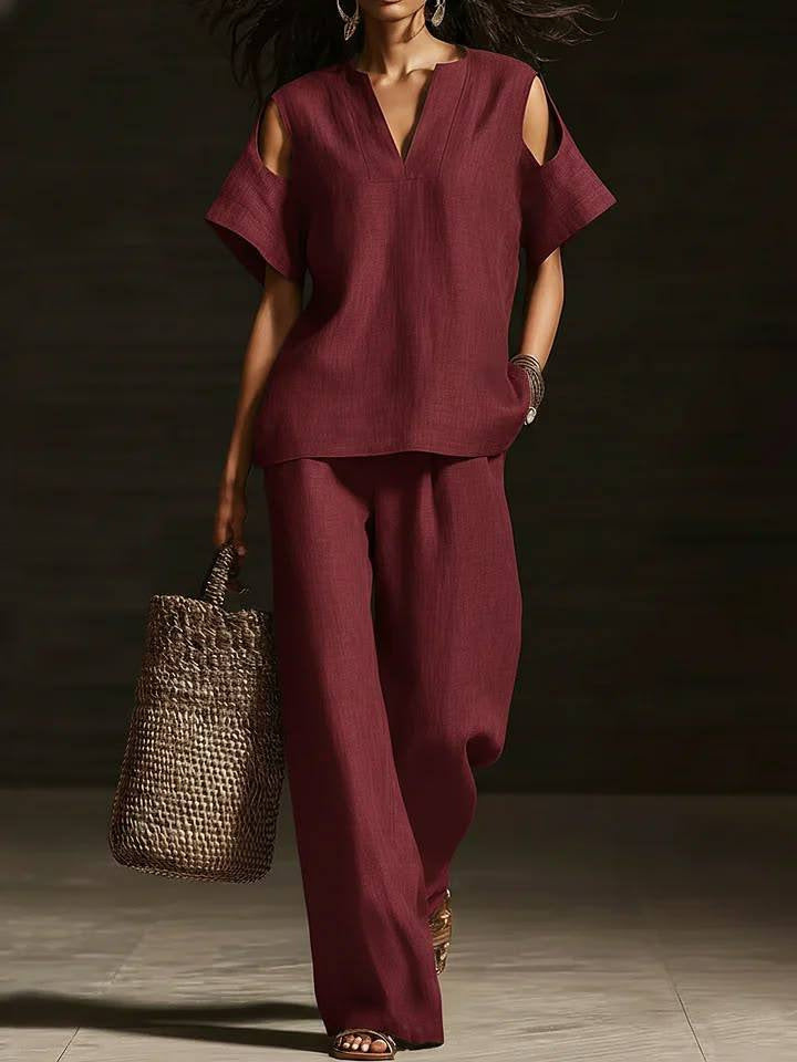Woman in a burgundy outfit holding a woven bag against a dark background