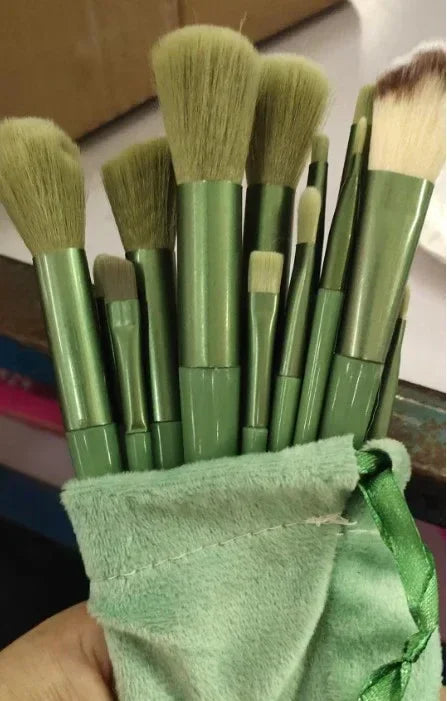 Set of green-handled makeup brushes in a soft green pouch for beauty essentials
