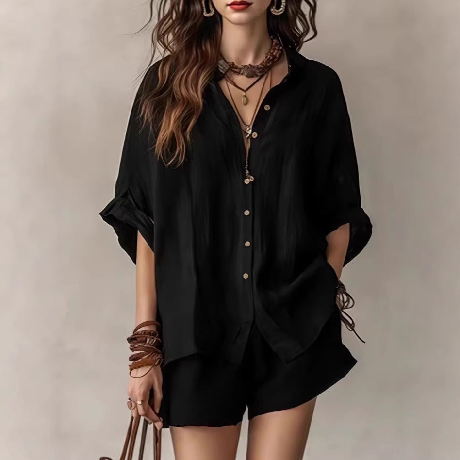 Person wearing a black outfit with layered necklaces and bracelets on a neutral background