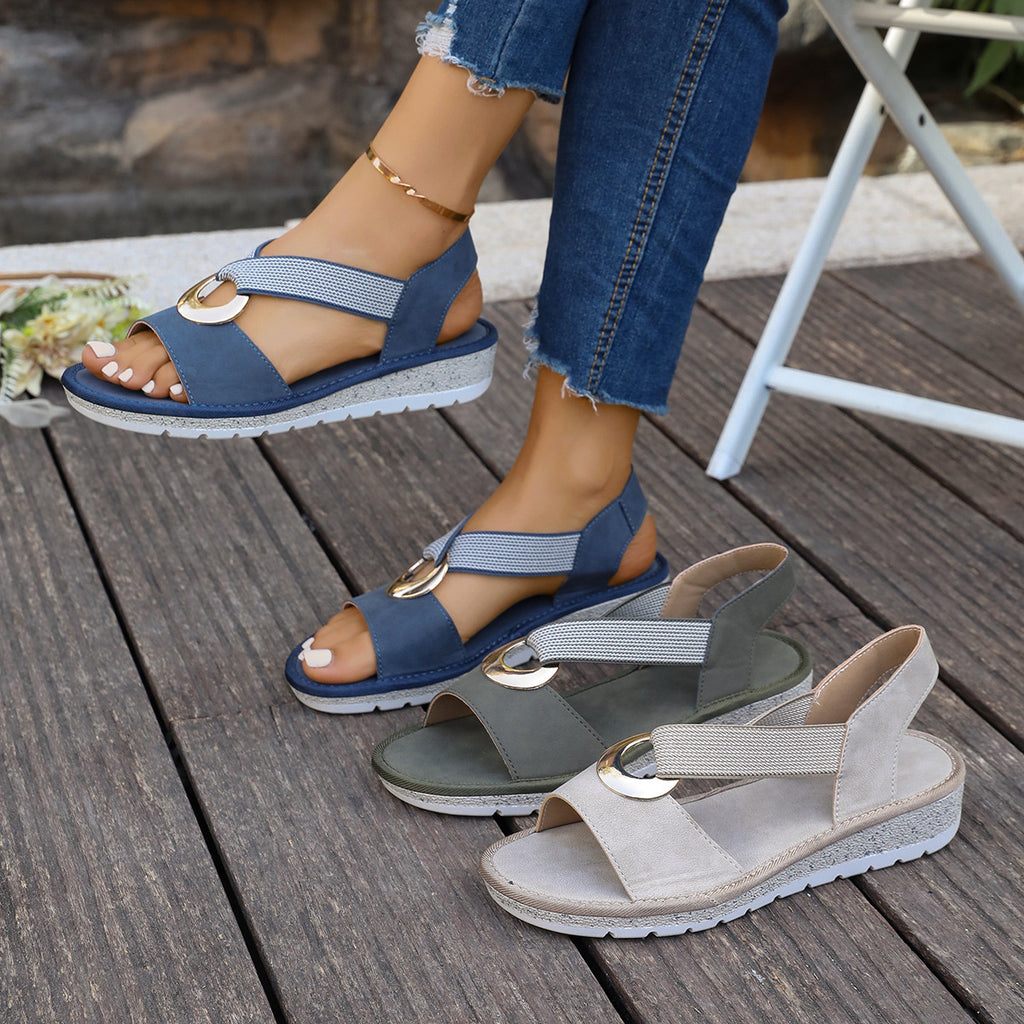 Blue sandals with gold buckles on a wooden floor