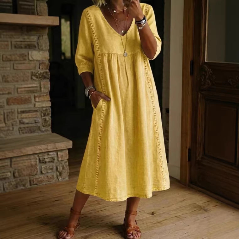 Person wearing a yellow dress standing in a room with wooden flooring and a stone fireplace.