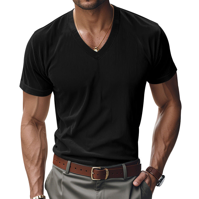Man wearing a black V-neck t-shirt and gray pants with a brown belt.