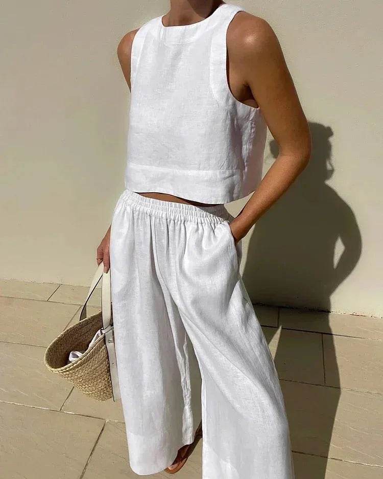 Woman in white sleeveless crop top and wide leg pants, holding straw bag, ZA-Zola fashion