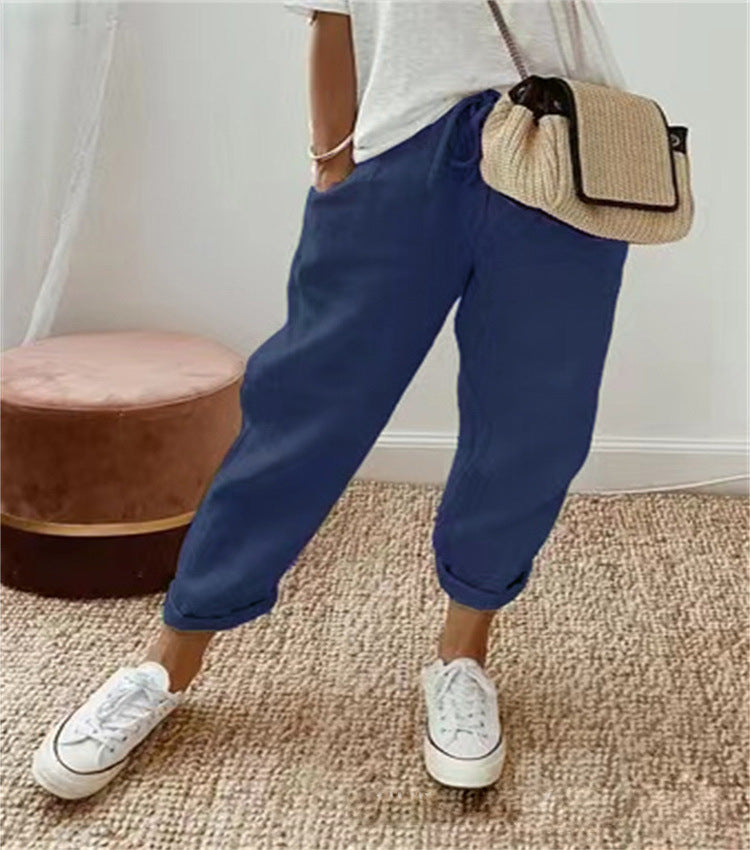 Person wearing blue pants, white sneakers, and a beige bag indoors.