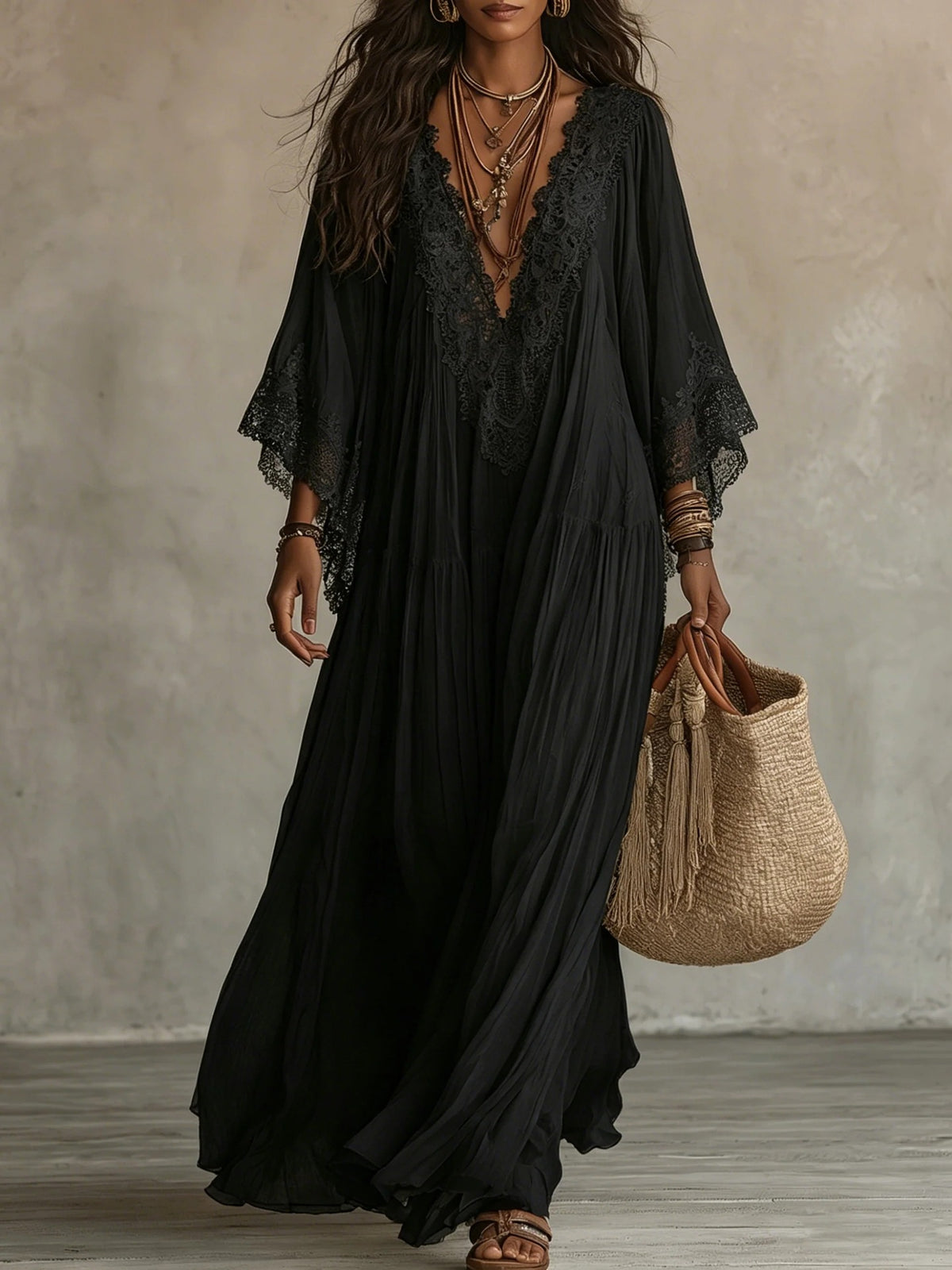 Woman wearing a black lace dress holding a woven bag against a neutral background