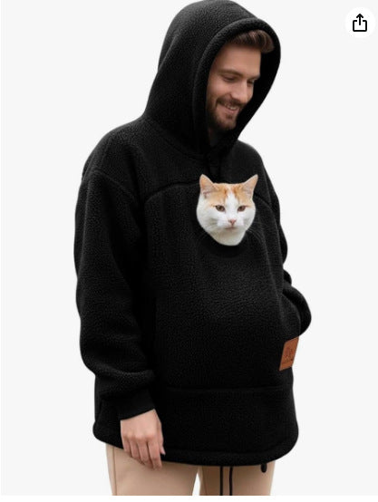Person wearing a black hoodie with a cat pocket, featuring a cat inside.