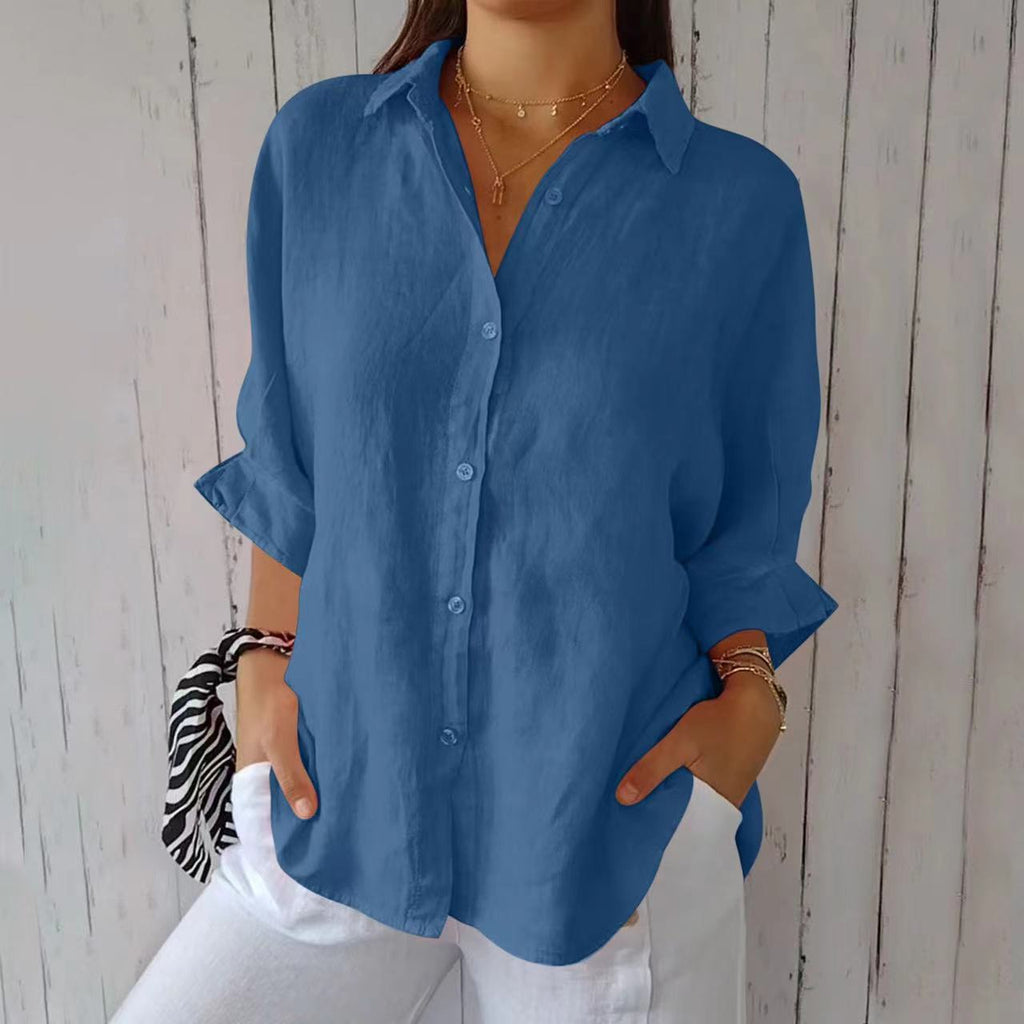 Person wearing a blue shirt with rolled-up sleeves against a wooden background