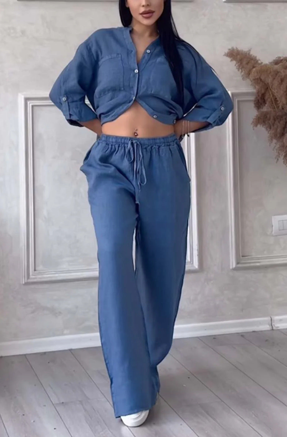 Person wearing a blue outfit in a room with light-colored walls and wooden floor.