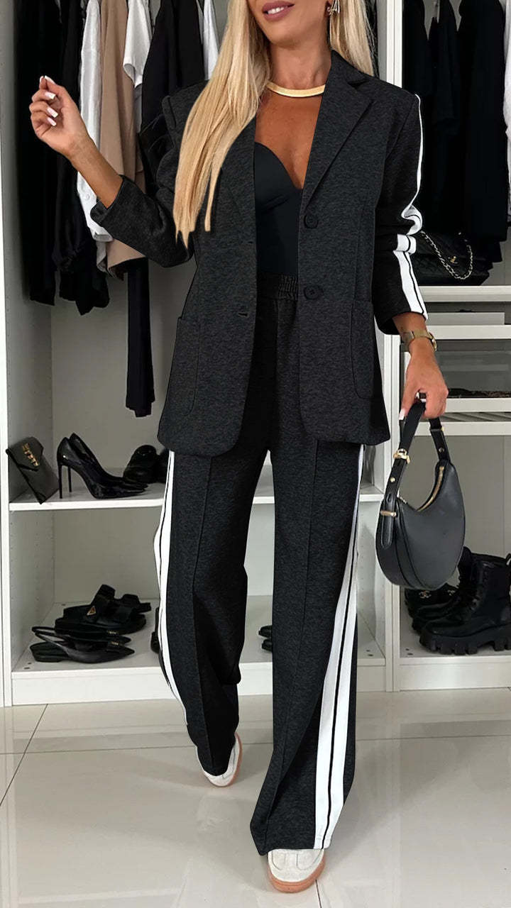 Woman in a black suit with white stripes standing in a closet.