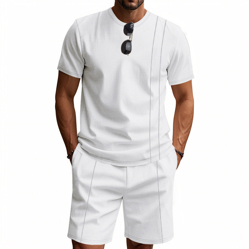 Man wearing a white short-sleeve shirt and shorts set with sunglasses on a white background