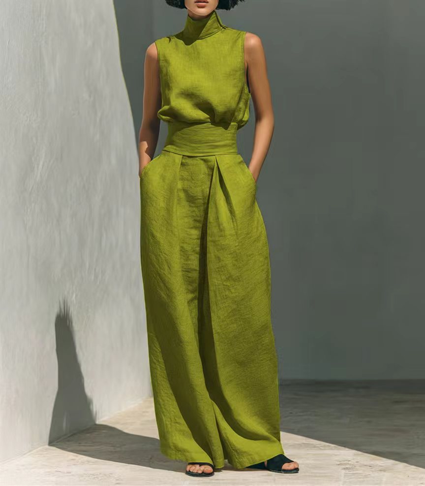 Person wearing a green outfit standing against a gray wall.