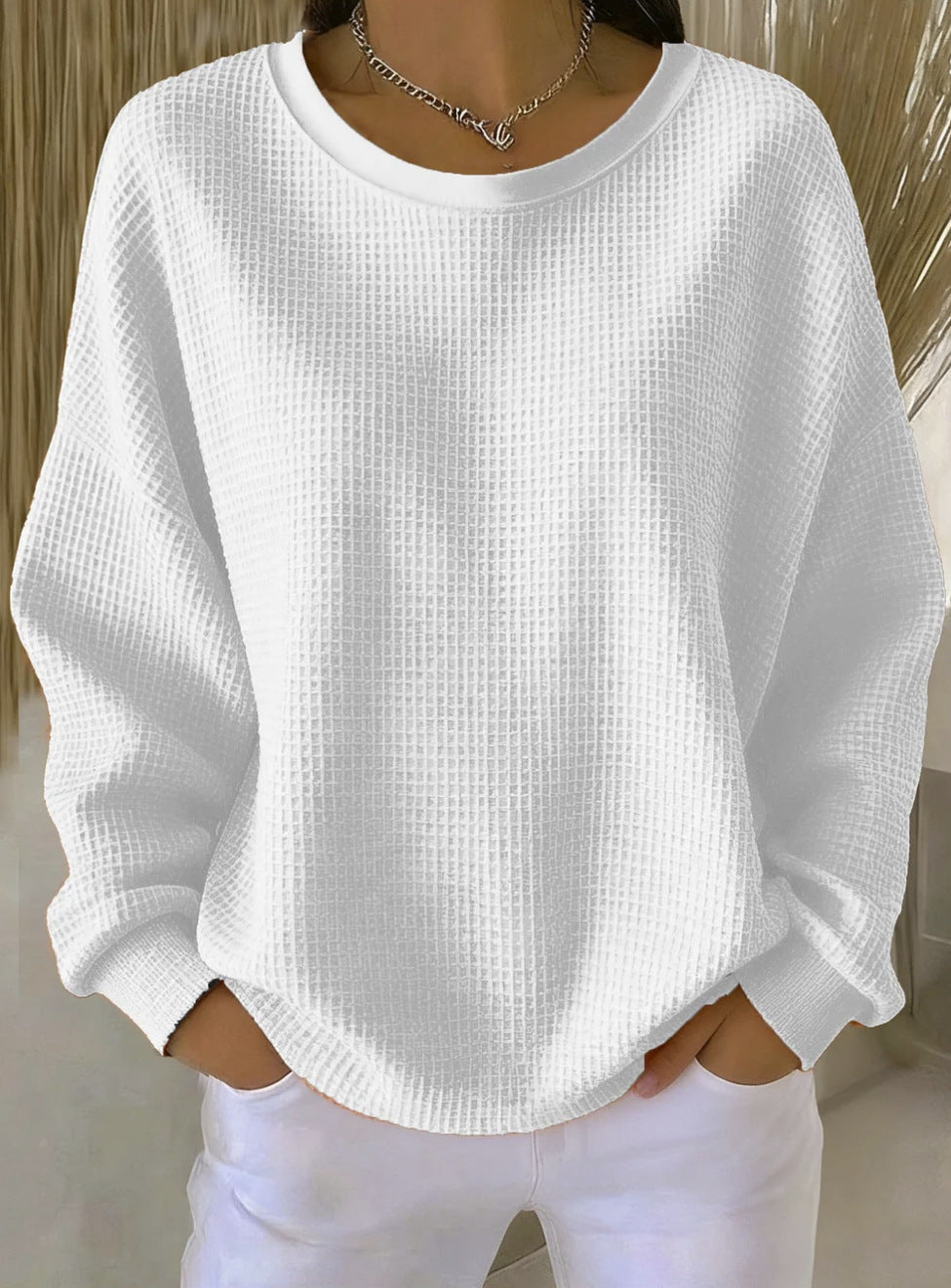 White textured sweater worn by a person against a neutral background