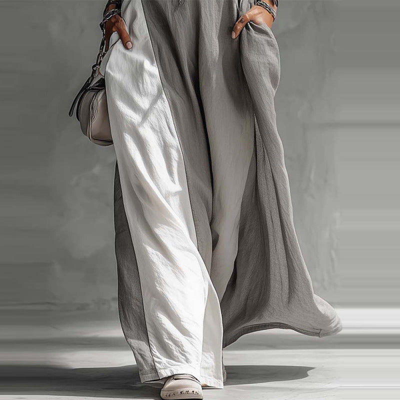Person wearing a long, light gray garment with wide-leg pants against a neutral background