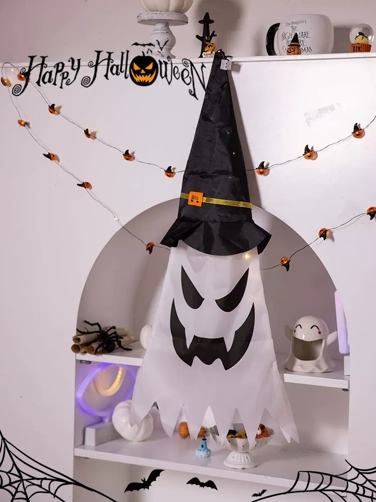 Halloween-themed decoration with a ghost and witch hat on a shelf.
