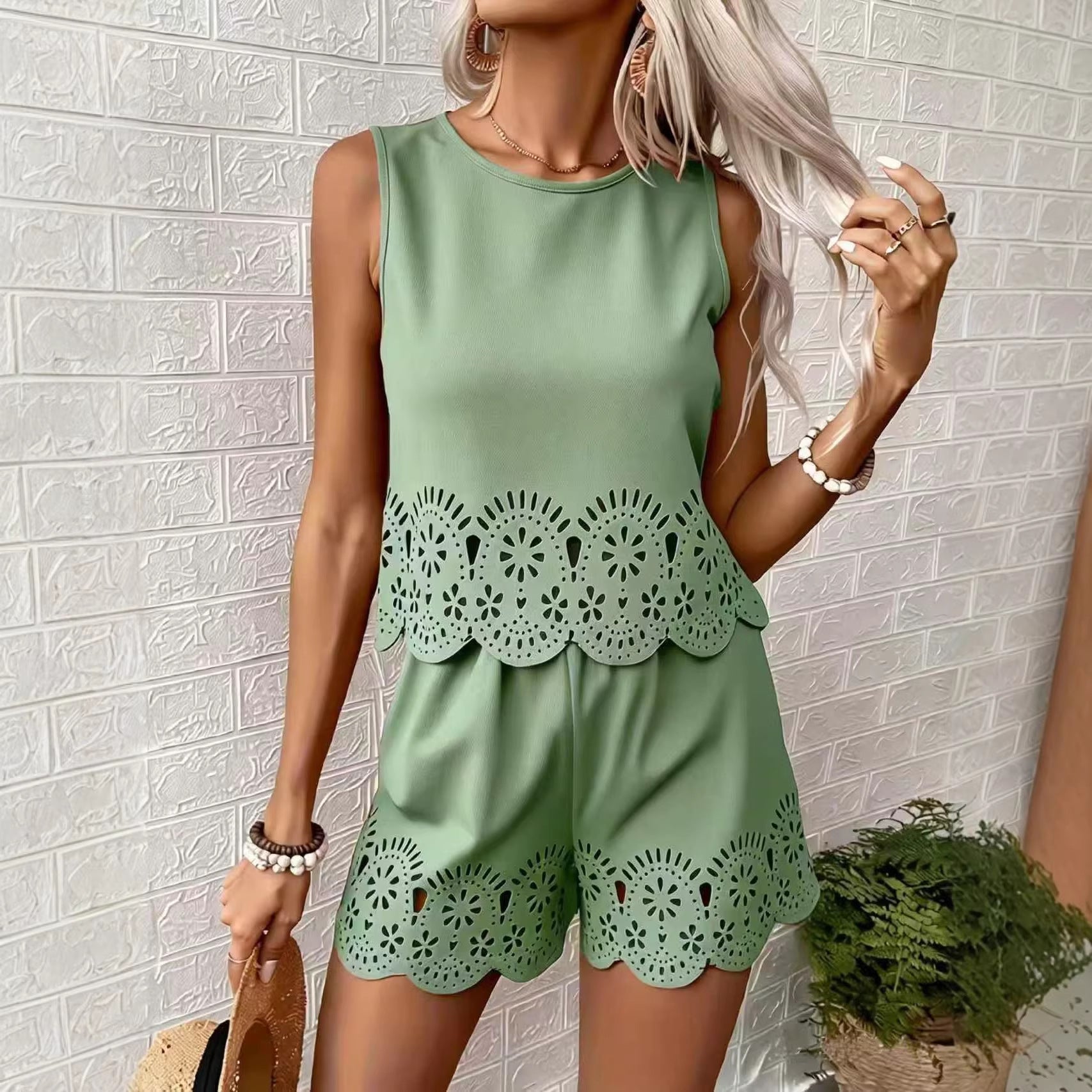 Woman wearing a green outfit with lace details against a white brick wall.