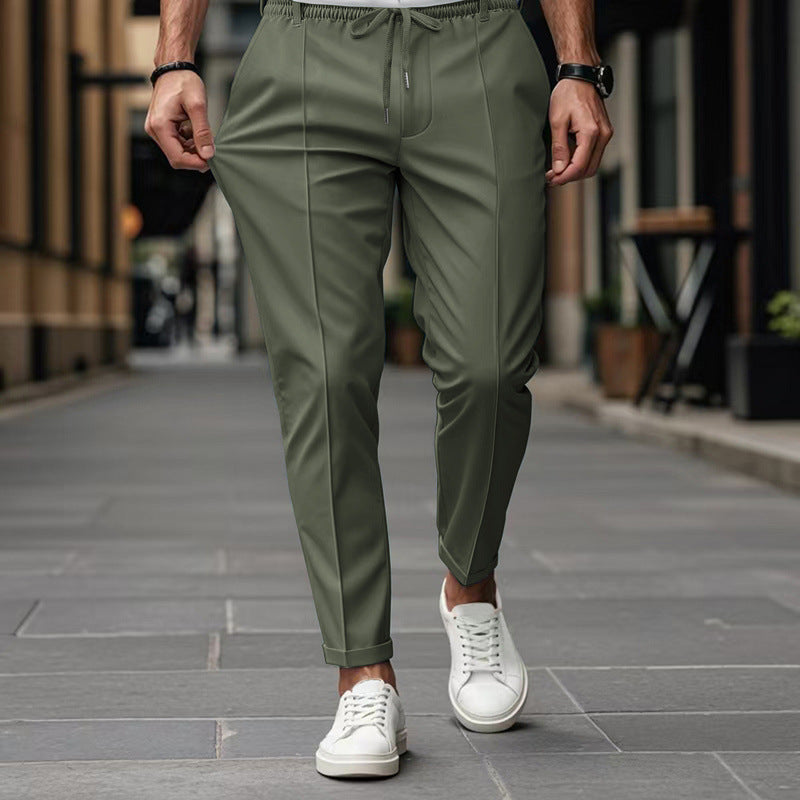 Person wearing olive green pants and white sneakers on a city street.