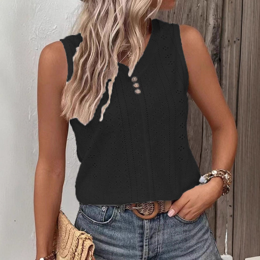 Woman wearing a black sleeveless top with buttons and jeans, standing against a wooden wall.