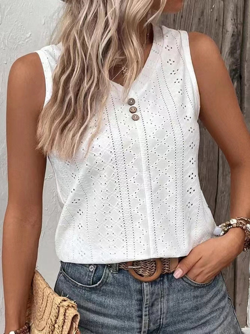 Woman wearing a white sleeveless top with button details and blue jeans against a wooden background.