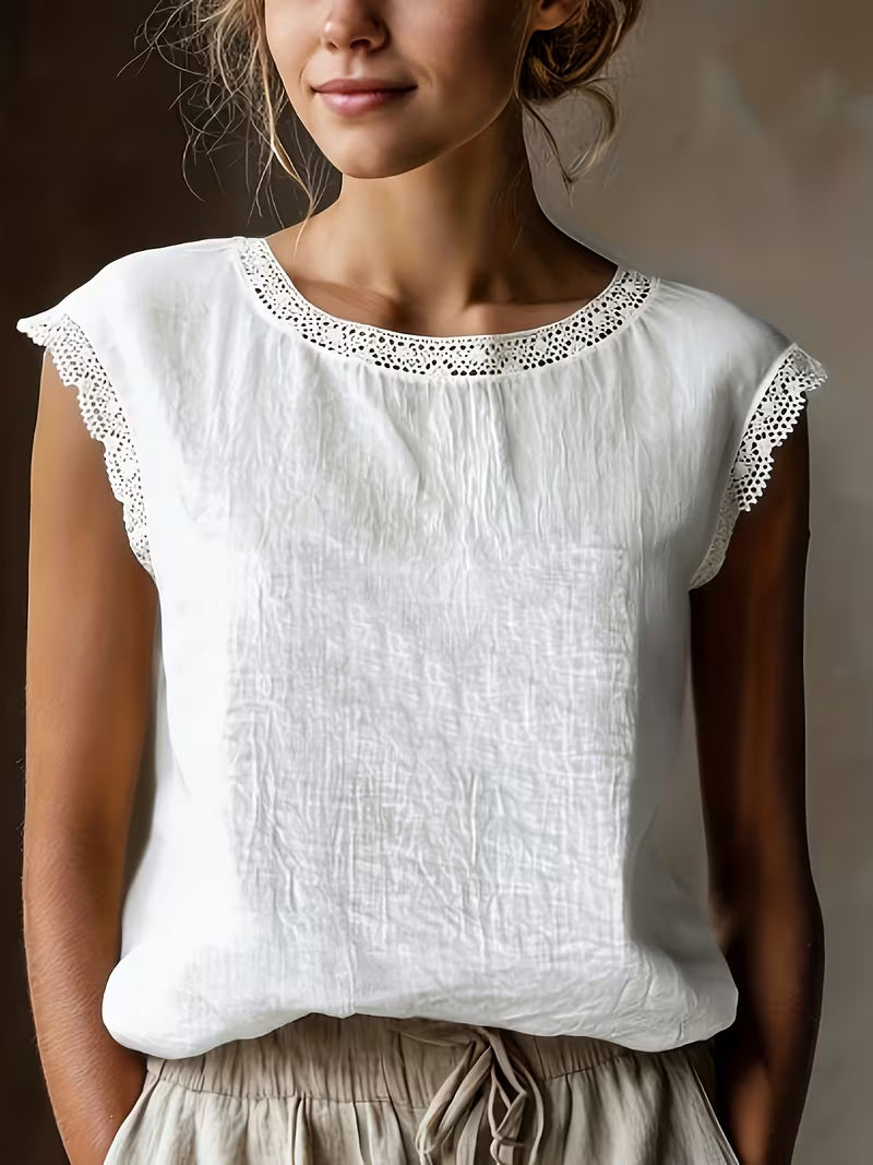 Woman wearing a white top with lace details on a plain background