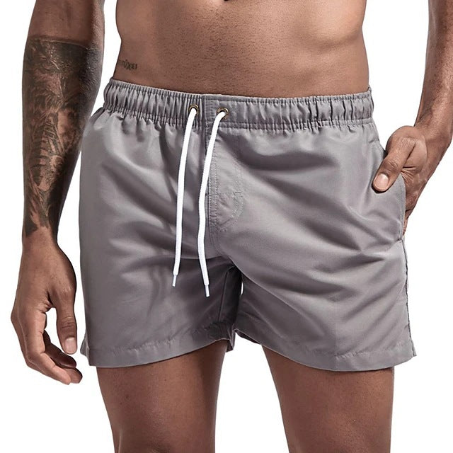 Gray swim shorts with a white drawstring on a neutral background
