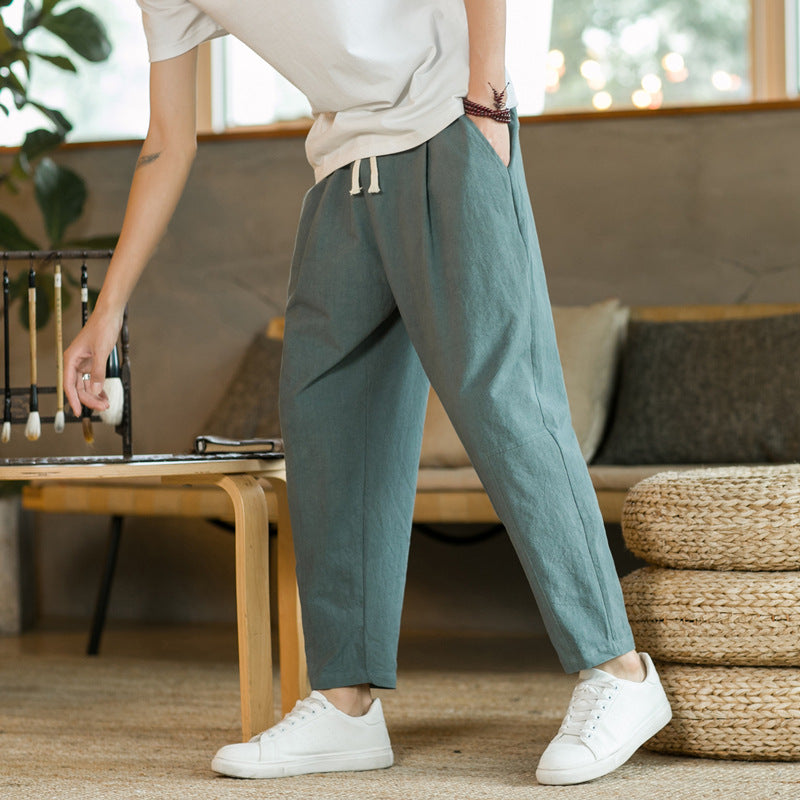 Person wearing teal pants and white sneakers in a living room setting