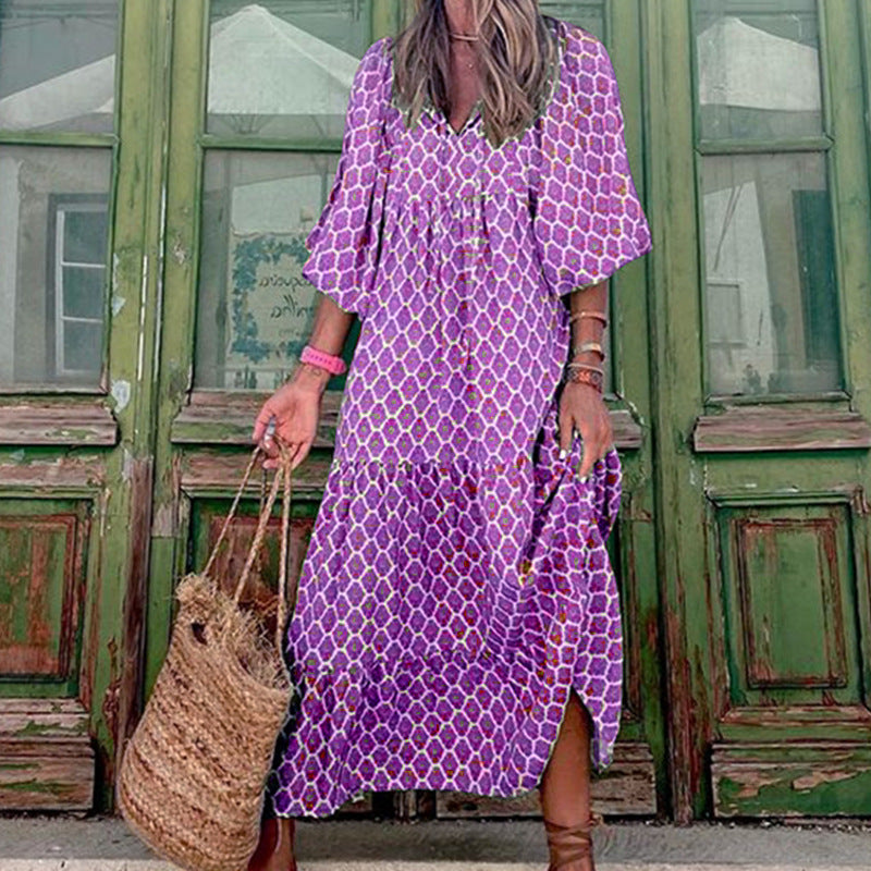Woman wearing a purple patterned dress standing in front of a green door.