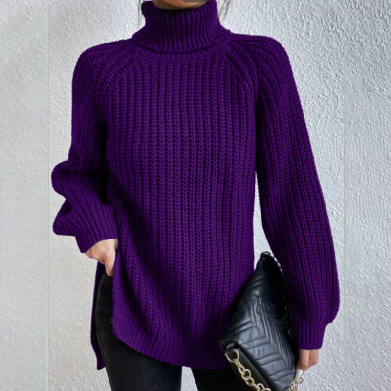 Person wearing a purple knitted sweater holding a black handbag against a light gray background