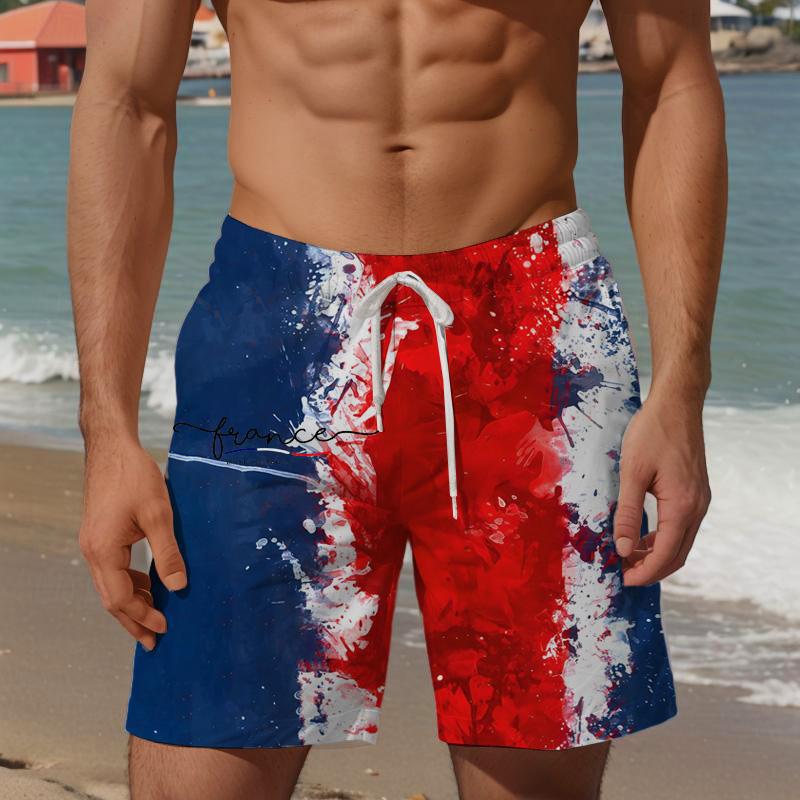 Person wearing red, white, and blue swim shorts on a beach.