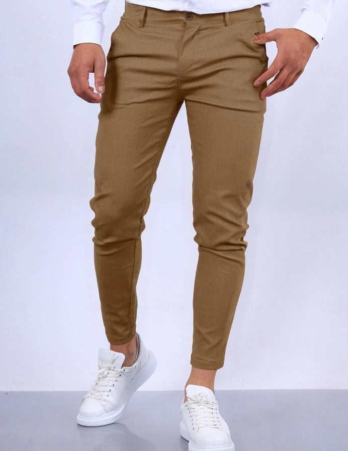 Person wearing brown pants and white sneakers on a white background