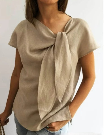 Beige top with a knot detail worn by a person on a plain background