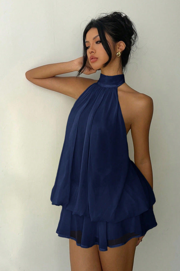 Woman wearing a navy blue halter dress against a plain background