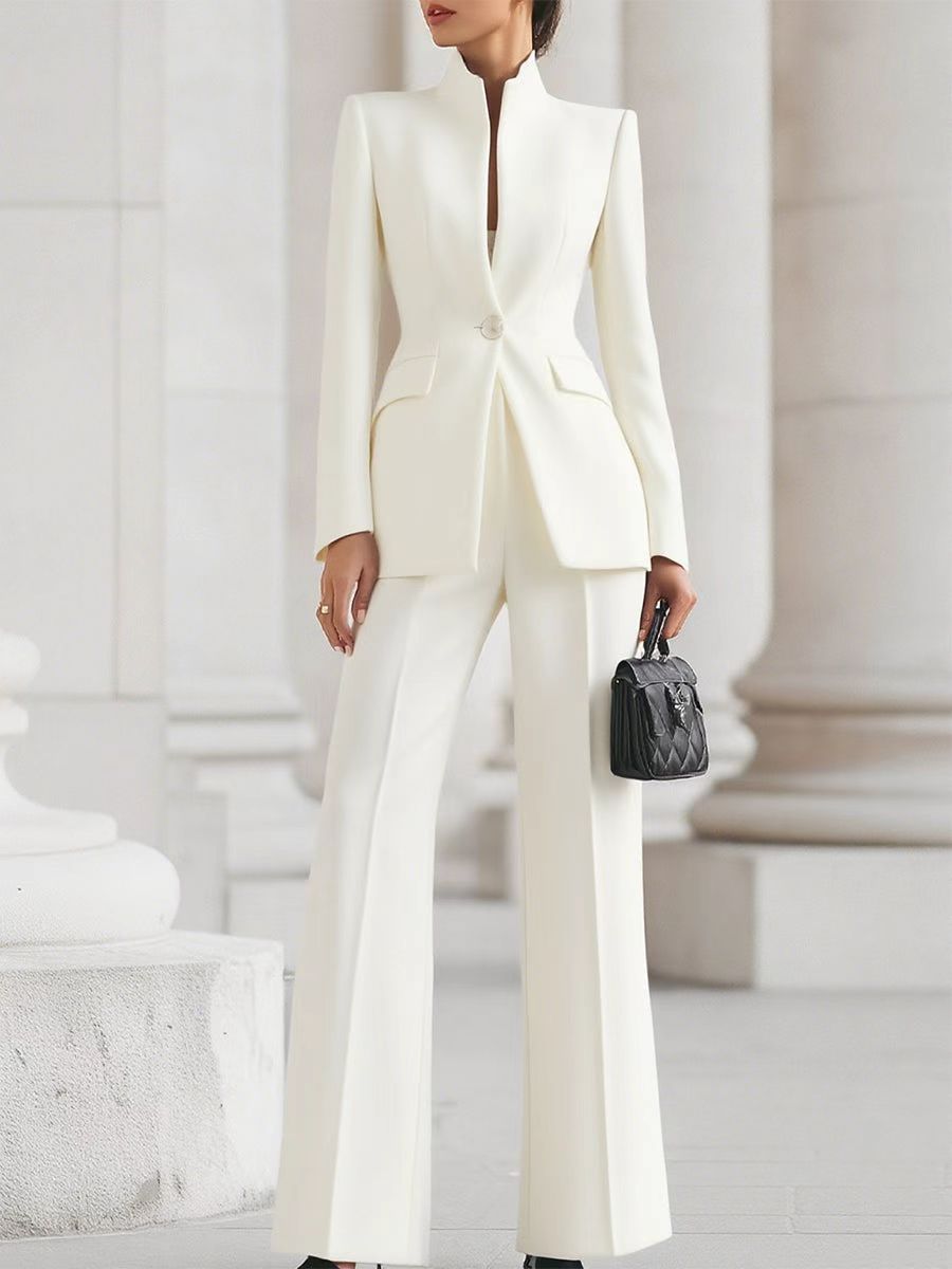 Person wearing a white suit with a black handbag in an elegant setting