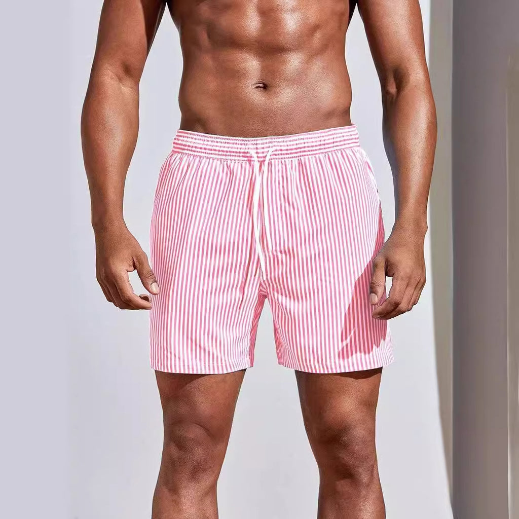 Person wearing pink and white striped swim shorts on a plain background
