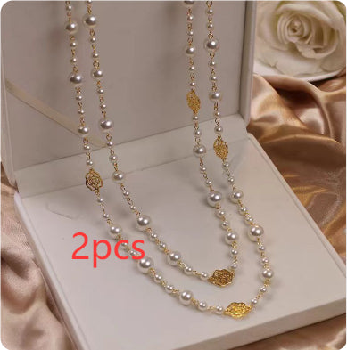 Two pearl necklaces with gold accents in a white box on a beige fabric background.