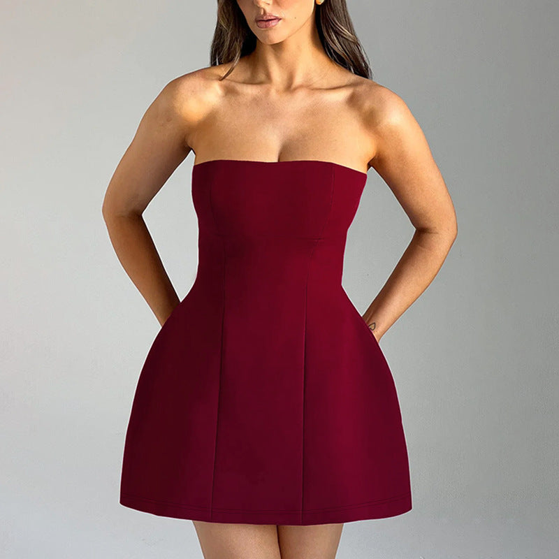 Woman wearing a strapless burgundy dress against a gray background