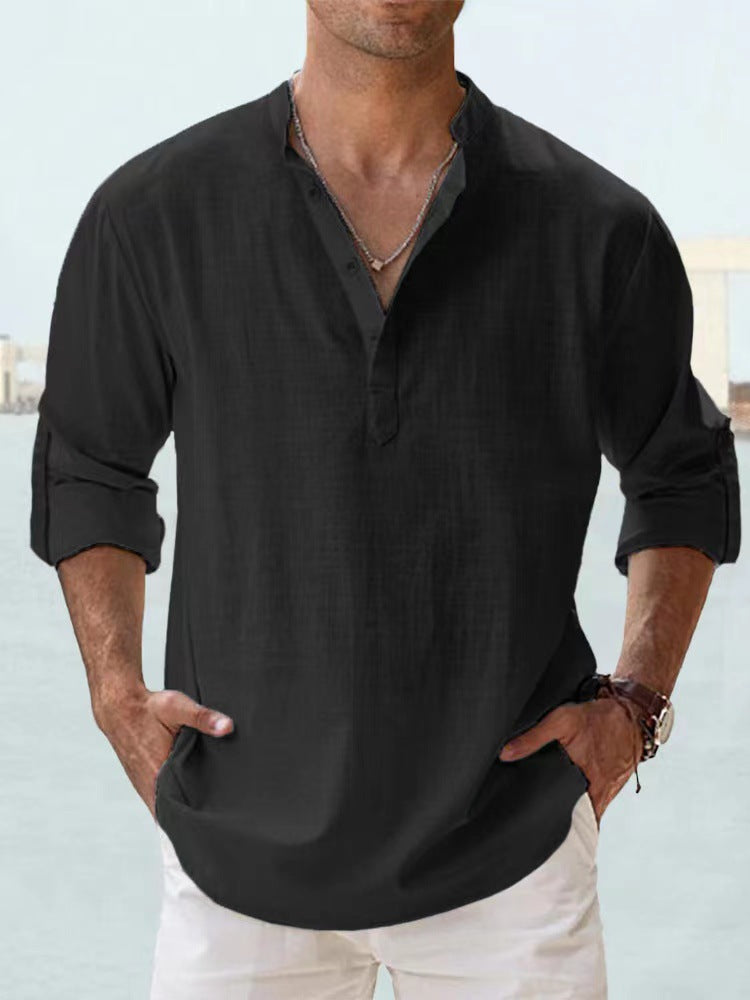 Man wearing a black shirt with rolled-up sleeves against a light background