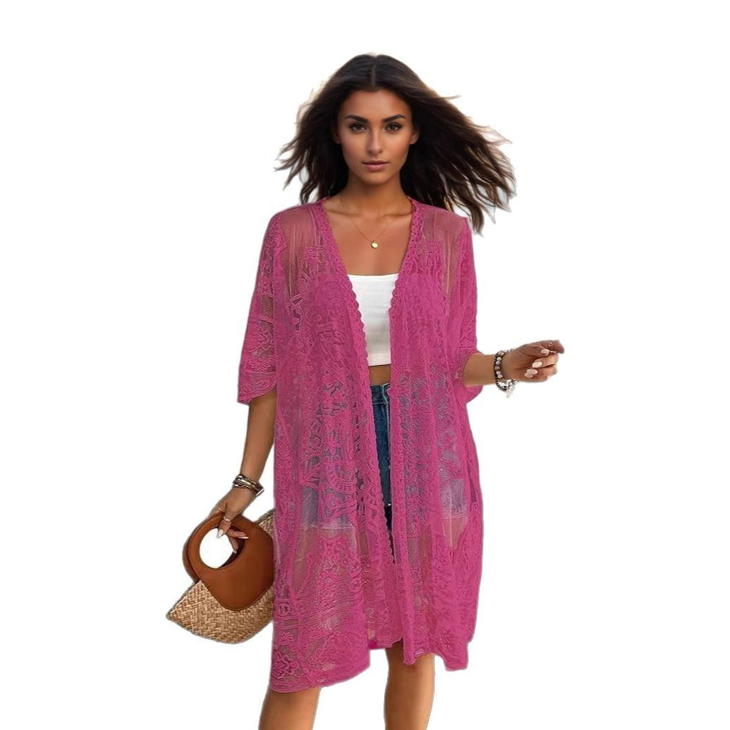 Woman wearing a pink lace kimono over a white top and blue jeans, holding a brown bag on a white background.